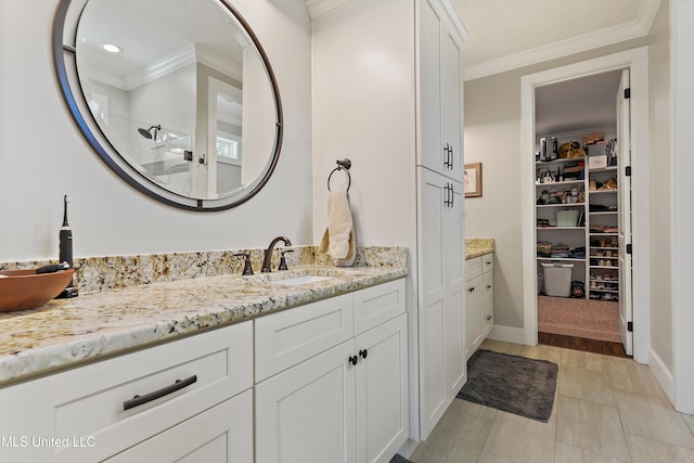 802 Old Spanish Trl, Bay Saint Louis, MS 39520 - bathroom featuring crown molding, vanity, tiled shower, a spacious closet, and baseboards