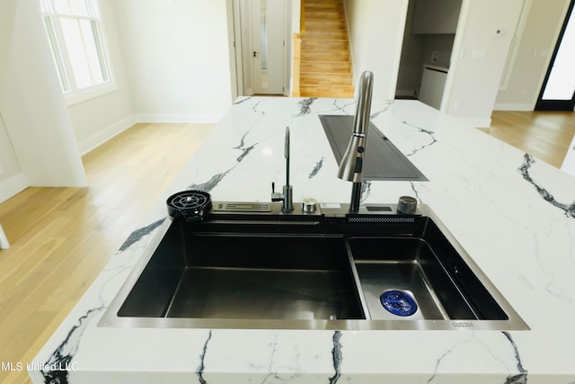 room details with stone counters, light hardwood / wood-style floors, and sink