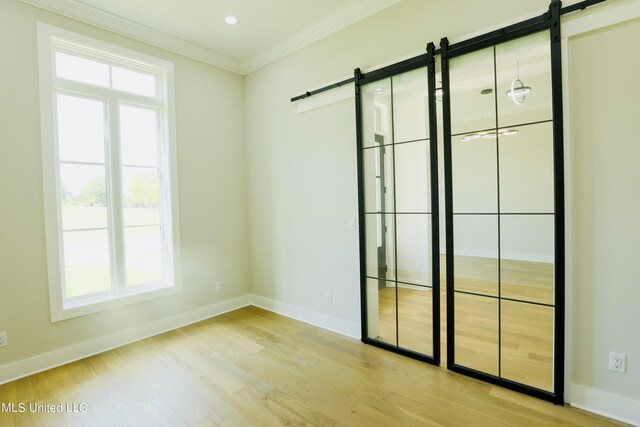 138 Genoa Dr, Madison, MS 39110 - empty room featuring a barn door, crown molding, baseboards, and light wood-style flooring