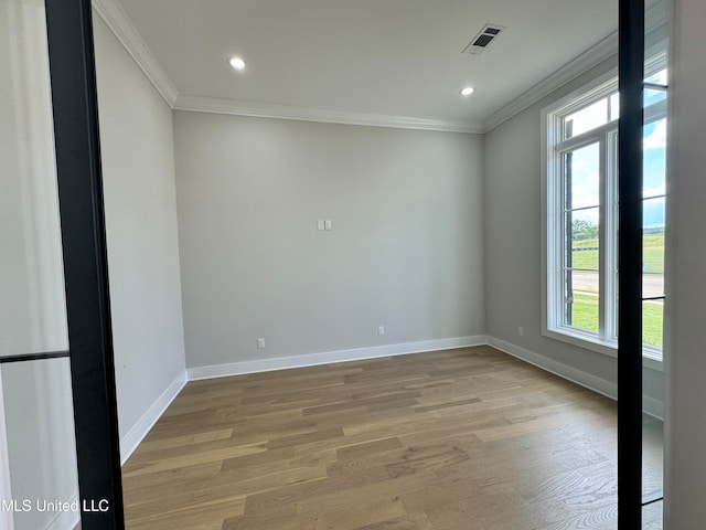 empty room with a wealth of natural light, hardwood / wood-style floors, and crown molding