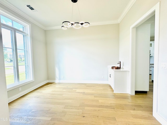 unfurnished dining area featuring crown molding, sink, and light wood-type flooring