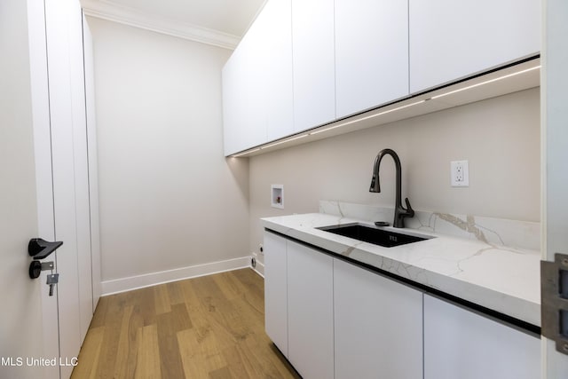 laundry room featuring cabinets, washer hookup, light wood-type flooring, crown molding, and sink