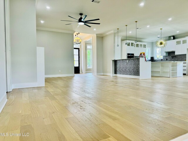 unfurnished living room featuring light hardwood / wood-style floors, crown molding, and ceiling fan