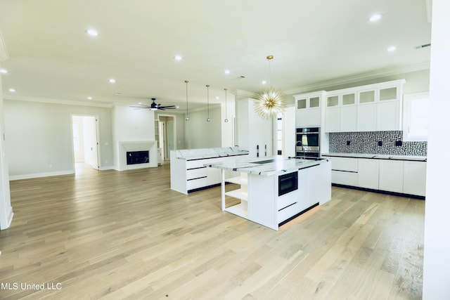 kitchen featuring a kitchen island, light hardwood / wood-style floors, pendant lighting, white cabinets, and ornamental molding