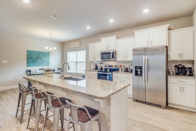 5251 Fairbury Way, Diberville, MS 39540 - kitchen with appliances with stainless steel finishes, light wood finished floors, a kitchen island with sink, a breakfast bar area, and recessed lighting