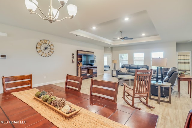 5251 Fairbury Way, Diberville, MS 39540 - dining area with a tray ceiling, a ceiling fan, baseboards, light wood-style flooring, and a chandelier