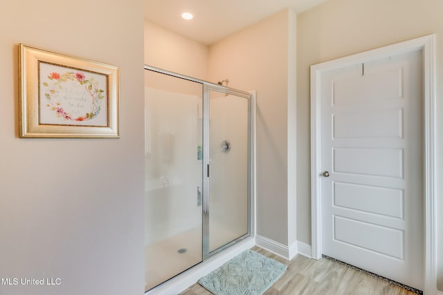 bathroom with hardwood / wood-style flooring and an enclosed shower