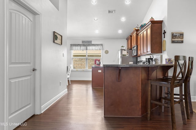 13703 Windwood Dr, Gulfport, MS 39503 - kitchen with refrigerator, stainless steel microwave, dark wood-style flooring, a breakfast bar area, and recessed lighting