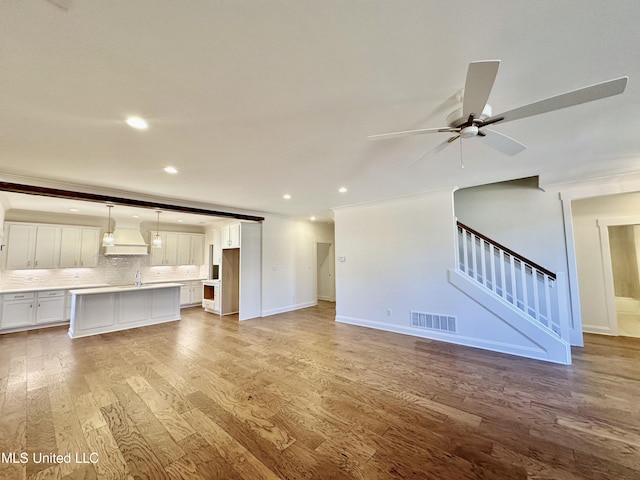 unfurnished living room with ceiling fan and light hardwood / wood-style flooring