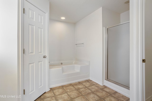 bathroom with a textured ceiling and separate shower and tub