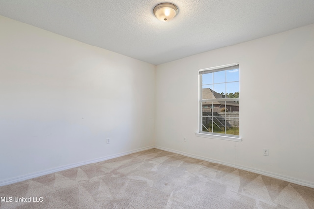 empty room featuring a textured ceiling and light colored carpet