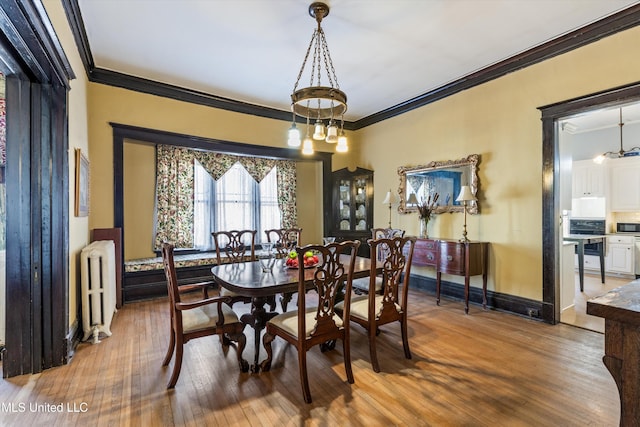 dining area with radiator, crown molding, baseboards, and wood finished floors