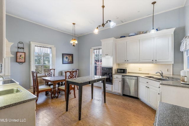 kitchen featuring a sink, wood finished floors, white cabinets, black appliances, and decorative light fixtures