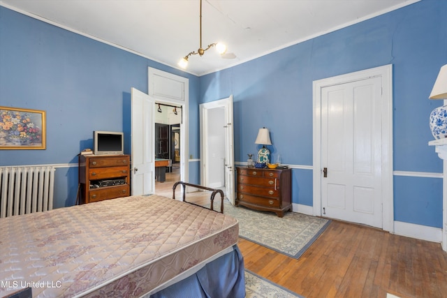 bedroom featuring radiator heating unit, wood finished floors, and baseboards