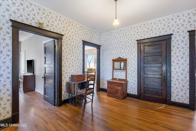 foyer featuring crown molding, dark wood finished floors, baseboards, and wallpapered walls