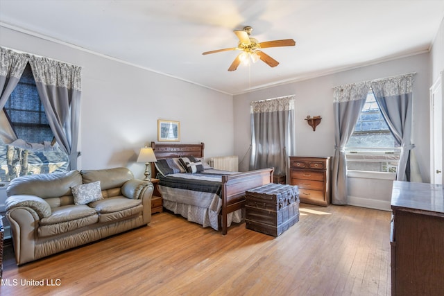 bedroom featuring light wood finished floors, baseboards, ornamental molding, and a ceiling fan