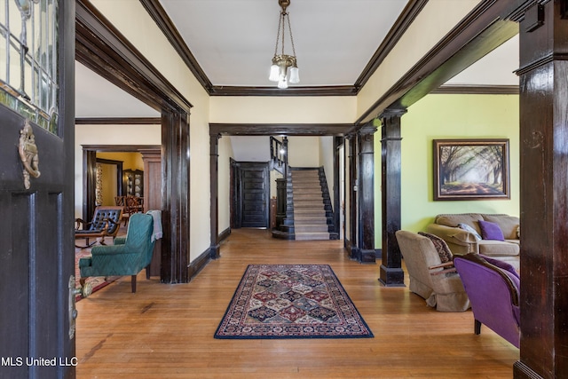 foyer entrance featuring crown molding, wood finished floors, and ornate columns