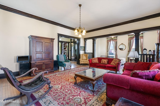 living area featuring ornamental molding, a notable chandelier, ornate columns, and wood finished floors