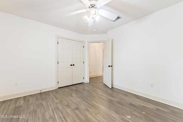 7635 Fairway Dr, Diamondhead, MS 39525 - unfurnished bedroom with wood finished floors, baseboards, a closet, and a ceiling fan