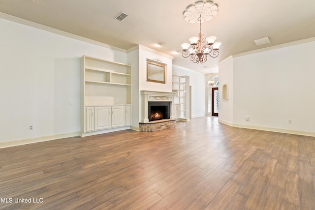 7635 Fairway Dr, Diamondhead, MS 39525 - unfurnished living room with a chandelier, wood finished floors, a brick fireplace, baseboards, and ornamental molding