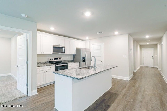 kitchen with appliances with stainless steel finishes, light wood-type flooring, a kitchen island with sink, sink, and white cabinets