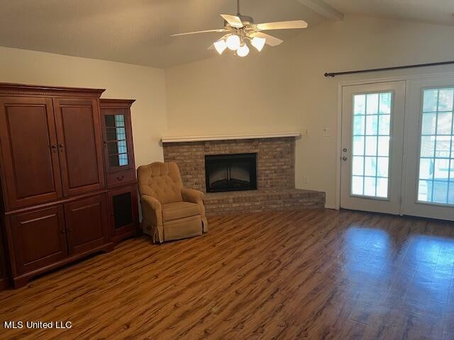 unfurnished living room featuring dark wood-type flooring, ceiling fan, vaulted ceiling with beams, and a fireplace