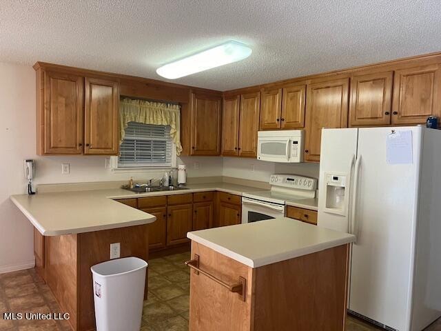 kitchen featuring white appliances, sink, a kitchen island, a textured ceiling, and kitchen peninsula