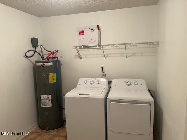 washroom featuring water heater, washer and clothes dryer, and a textured ceiling