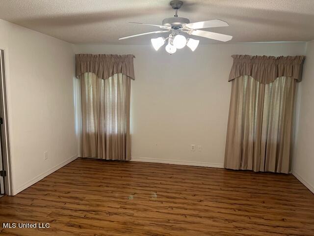 empty room featuring a textured ceiling, dark wood-type flooring, and ceiling fan