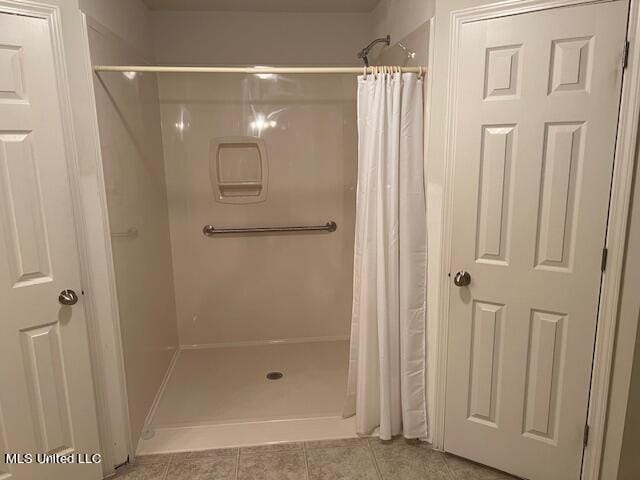 bathroom with curtained shower and tile patterned flooring