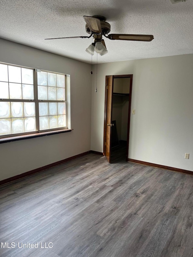 unfurnished bedroom featuring hardwood / wood-style flooring, ceiling fan, and a textured ceiling