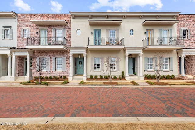 multi unit property with brick siding, stucco siding, and a balcony