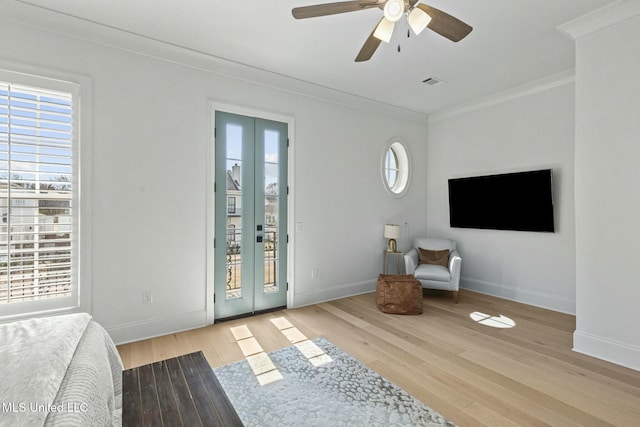 interior space with visible vents, a ceiling fan, wood finished floors, crown molding, and baseboards