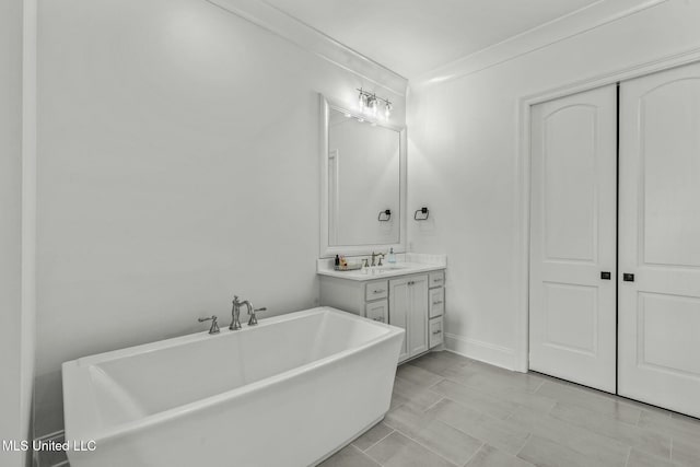 full bathroom with vanity, a freestanding tub, baseboards, and ornamental molding