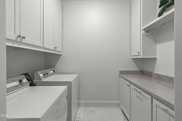 washroom featuring washing machine and dryer, cabinet space, marble finish floor, and baseboards