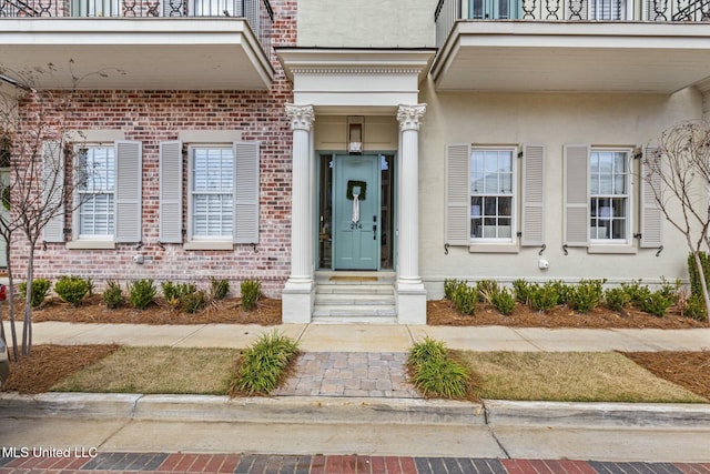 entrance to property featuring brick siding and stucco siding