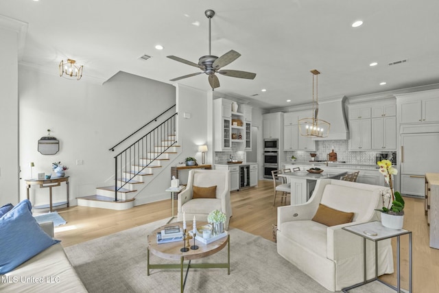 living room featuring visible vents, stairway, recessed lighting, ceiling fan with notable chandelier, and light wood-style floors