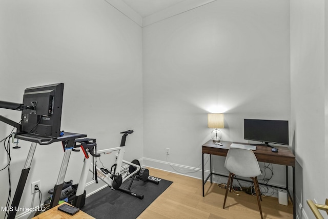 exercise room with baseboards and wood finished floors