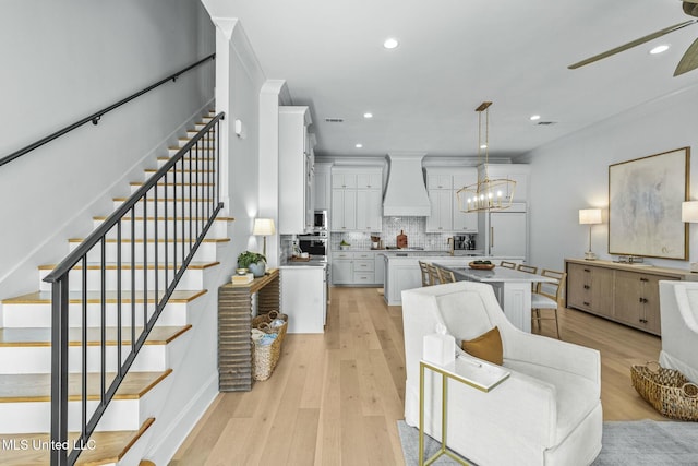 kitchen with white cabinetry, custom exhaust hood, light wood-type flooring, and a kitchen island