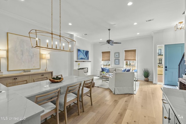 kitchen with light wood-style flooring, light stone countertops, visible vents, and ornamental molding