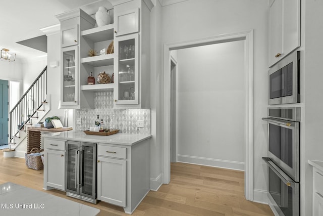 kitchen featuring stainless steel microwave, light wood finished floors, beverage cooler, and open shelves