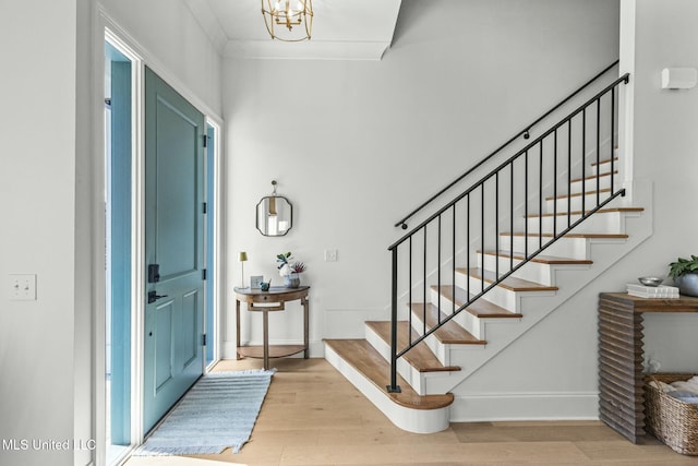 entrance foyer with a notable chandelier, stairway, baseboards, and wood finished floors