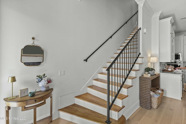 stairway with visible vents, baseboards, and wood finished floors