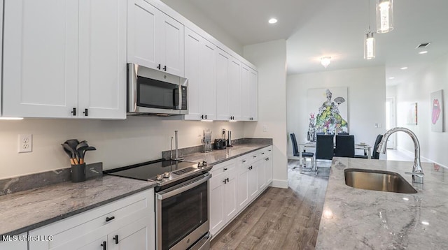 132 Markham Dr, Gulfport, MS 39507 - kitchen featuring appliances with stainless steel finishes, a sink, white cabinetry, wood finished floors, and light stone countertops