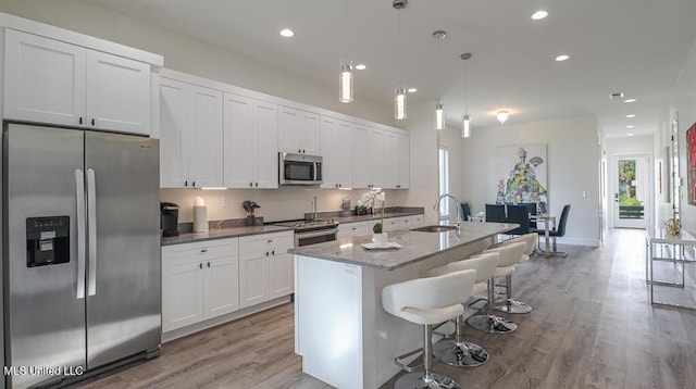 132 Markham Dr, Gulfport, MS 39507 - kitchen featuring appliances with stainless steel finishes, light wood-type flooring, a sink, an island with sink, and recessed lighting
