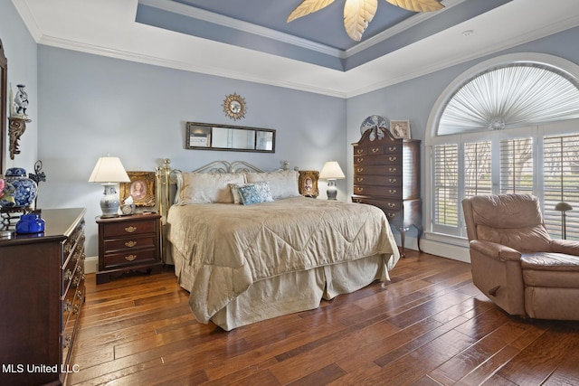 bedroom with dark wood-type flooring, a raised ceiling, ceiling fan, and ornamental molding