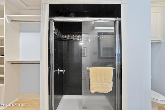 bathroom with hardwood / wood-style flooring, toilet, and an enclosed shower