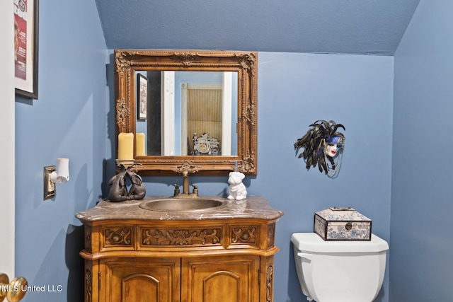 bathroom with a textured ceiling, vanity, and toilet