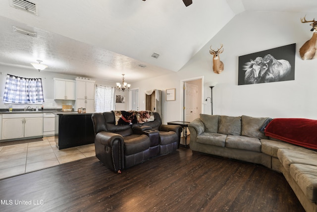 living room with a textured ceiling, light wood-type flooring, a wealth of natural light, and lofted ceiling