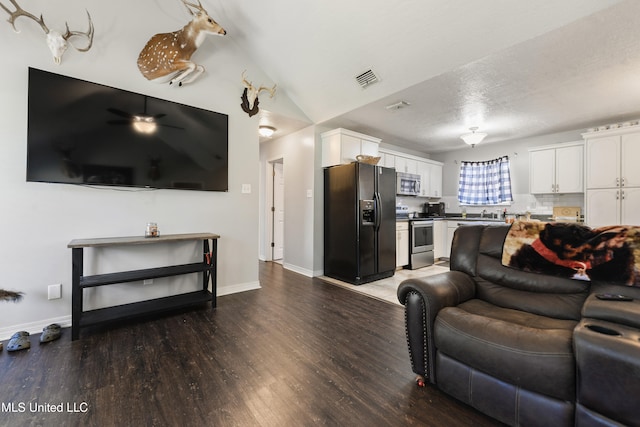 living room with wood-type flooring, a textured ceiling, and lofted ceiling